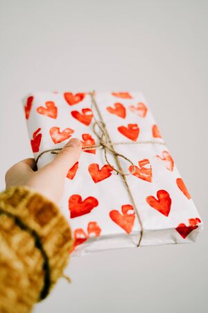 a gift in homemade wrapping paper with red hearts for Valentine's day