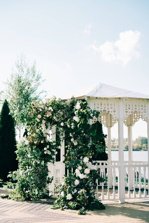 wedding arch decorated with a beautiful floral arrangement of white flowers and fresh branches of greeneryの写真素材