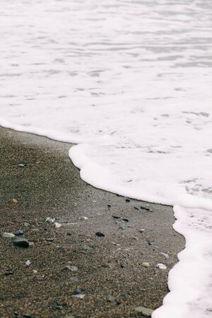 the sea wave arrives on the sandy shore .
