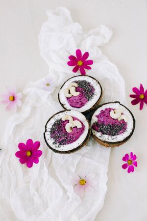 healthy Breakfast berry smoothie with Chia seeds and cashew nuts in a natural coconut plate with pink flowersの写真素材