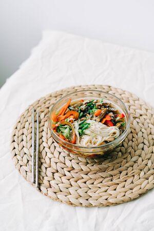 Japanese ramen soup in a glass plate with vegan ingredients, fresh vegetables in small plates, rice...
