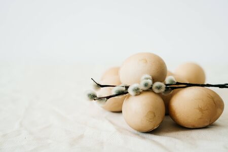 several Easter eggs of a fashionable pastel color with cracks lie on the table on a light tablecloth with branches of a budding willow. minimal style.Easter conceptの写真素材