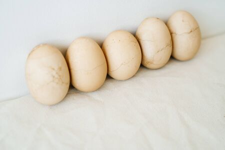 five Easter eggs trendy pastel colored with cracked shells on a white table against a white wall. minimal style. Easter concept.の写真素材