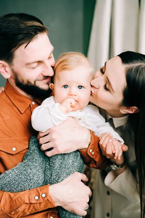 a beautiful young family of three. happy Father and mother hold their little son in their arms....