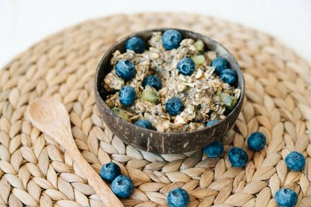oatmeal porridge in a bowl with blueberries and Chia seeds. Healthy Breakfast cereal, oatmeal cereal with fresh blueberries on a brown background of natural soft dried seaweed. Concept of clean foodの写真素材
