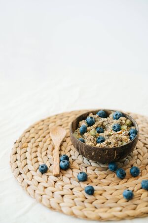 oatmeal porridge in bowl with fresh blueberries.Healthy vegan Breakfast cereals, against background of brown natural seaweed napkin and natural wooden bamboo spoon.Concept of clean foodの写真素材