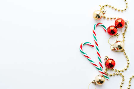 Christmas frame. Christmas balls, garland, red and golden decorations, christmas candy on white background. Flat lay, top view, copy space.の写真素材
