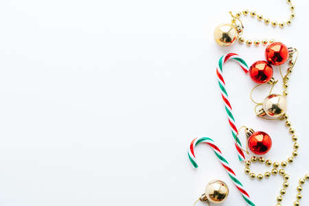 Christmas frame. Christmas balls, garland, red and golden decorations, christmas candy on white background. Flat lay, top view, copy space.の写真素材