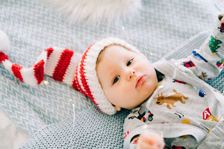 the child's first Christmas. a cute little boy in a Santa hat. lying on the bed. the view from the top. Christmas concept.の写真素材