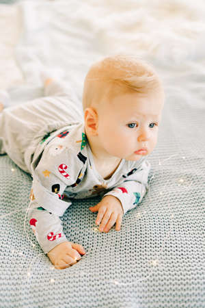 the child's first Christmas. a pensive sad little boy is lying in a festive costume on the bed...