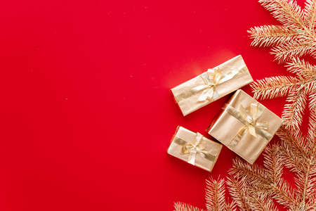 Red Christmas or new year's background, plain composition of golden Christmas gifts and golden fir branches, Flatlay, empty space for greeting text.christmas conceptの写真素材