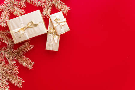 Red Christmas or new year's background, plain composition of golden Christmas gifts and golden fir...