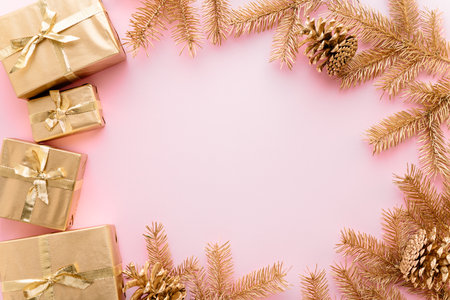 Pink Christmas or new year's background, plain composition of golden Christmas gifts and golden fir branches, Flatlay, empty space for greeting text.christmas conceptの写真素材