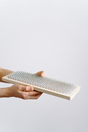 a woman of European appearance holds a wooden board with galvanized nails and puts her hand on top of the nails of the sadhu board. the trend of self-development. the concept of yogaの写真素材