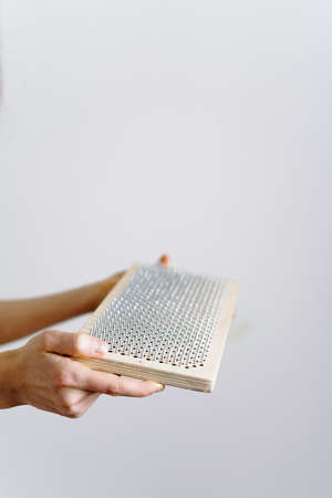 a woman of European appearance holds a wooden board with galvanized nails and puts her hand on top of the nails of the sadhu board. the trend of self-development. the concept of yogaの写真素材