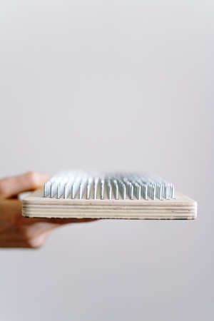 a woman of European appearance holds a wooden board with galvanized nails and puts her hand on top of the nails of the sadhu board. the trend of self-development. the concept of yogaの写真素材