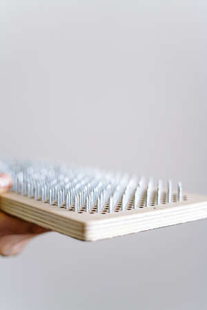 a woman of European appearance holds a wooden board with galvanized nails and puts her hand on top of the nails of the sadhu board. the trend of self-development. the concept of yogaの写真素材