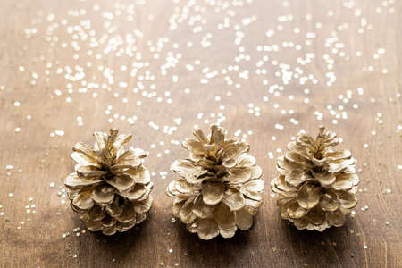 natural golden cones on a wooden table with gold spangles in the shape of stars, among fir branchesの写真素材