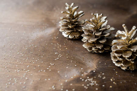 natural golden cones on a wooden table with gold spangles in the shape of stars, among fir branchesの写真素材