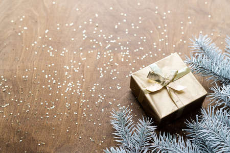 a golden gift box on a wooden table with gold spangles in the shape of stars, among the fir branchesの写真素材
