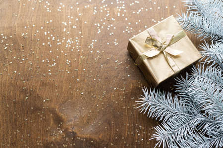 a golden gift box on a wooden table with gold spangles in the shape of stars, among the fir branchesの写真素材