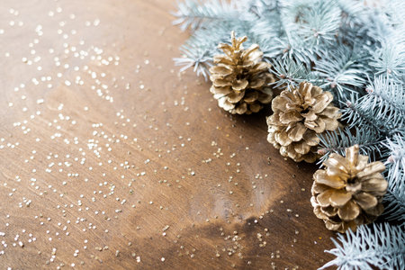 natural golden cones on a wooden table with gold spangles in the shape of stars, among fir branches.の写真素材