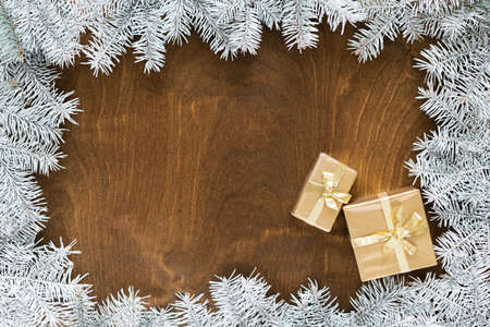 a golden gift box on a wooden table among fir branches with warm light bulbs. High quality photoの写真素材