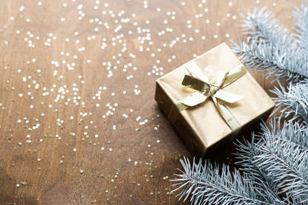 a golden gift box on a wooden table with gold spangles in the shape of stars, among the fir branches. High quality photoの写真素材