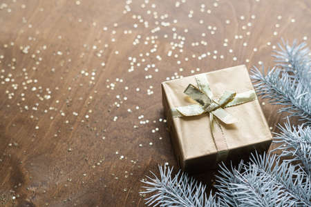 a golden gift box on a wooden table with gold spangles in the shape of stars, among the fir branches. High quality photoの写真素材