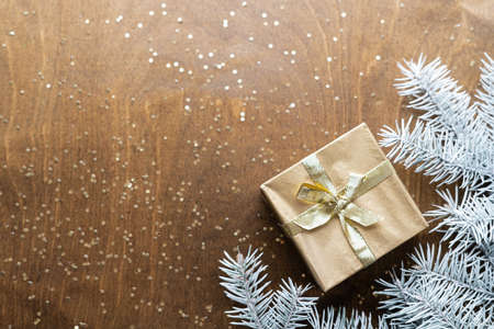 a golden gift box on a wooden table with gold spangles in the shape of stars, among the fir branches. High quality photoの写真素材