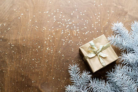a golden gift box on a wooden table with gold spangles in the shape of stars, among the fir branches. High quality photoの写真素材