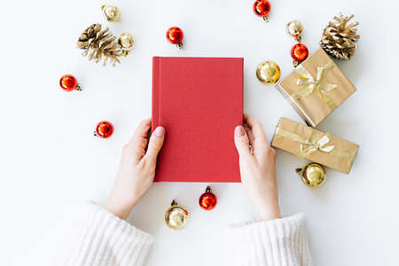 a red book in the hands of a young girl against the background of gifts and Christmas toys. the concept of Christmas. High quality photoの写真素材