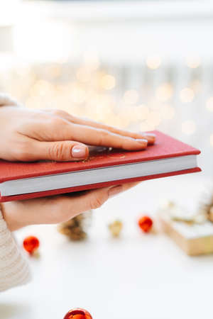 a red book in the hands of a young girl against the background of gifts and Christmas toys, a garland bokeh. the concept of Christmas. High quality photoの写真素材