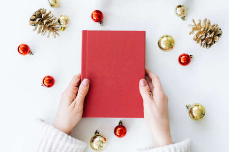 a red book in the hands of a young girl against the background of gifts and Christmas toys. the concept of Christmas. High quality photoの写真素材