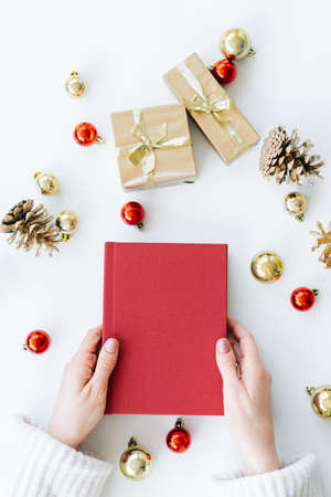 a red book in the hands of a young girl against the background of gifts and Christmas toys. the concept of Christmas. High quality photoの写真素材