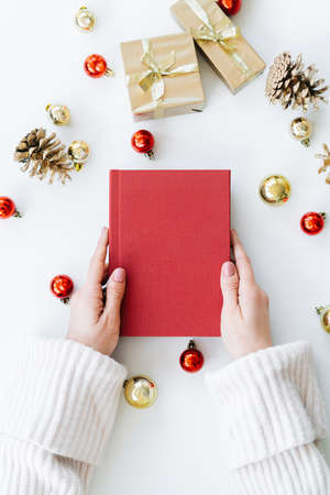 a red book in the hands of a young girl against the background of gifts and Christmas toys. the concept of Christmas. High quality photoの写真素材