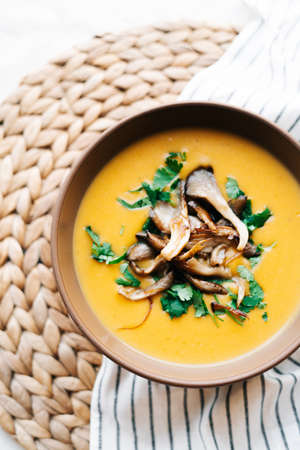 a plate of hot homemade pumpkin-coconut cream soup with fried mushrooms and fresh herbs. High quality photoの写真素材