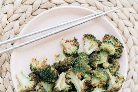 baked broccoli cabbage inflorescences in a pink plate on a woven napkinの写真素材
