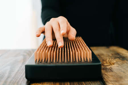 a sadhu board made of dark oak with copper nails on a wooden table. the girl runs her fingers over the copper nails. the yogic practice of standing on nailsの写真素材