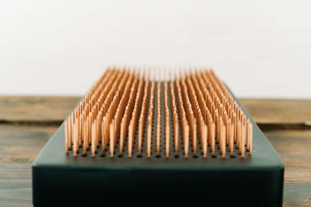 a sadhu board made of dark oak with copper nails on a wooden floor. the yogic practice of standing on nailsの写真素材