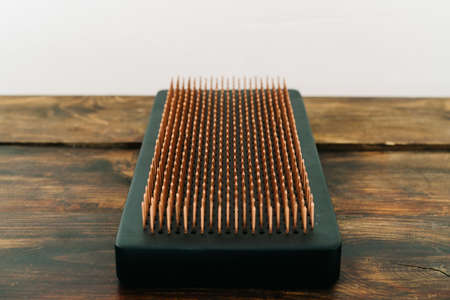 a sadhu board made of dark oak with copper nails on a wooden floor. the yogic practice of standing on nailsの写真素材