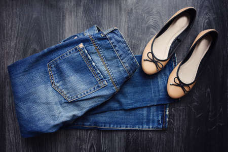 Boyfriend jeans and ballet shoes on black wooden background.の写真素材
