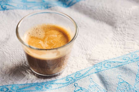 Espresso in glass on white kitchen towel with blue ornament.の写真素材