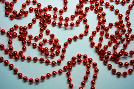 New Year's and Christmas red beads for the New Year tree are randomly scattered on a white fabric background.の写真素材