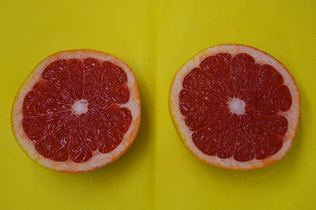 Ripe and tasty fruits, fresh grapefruit cut in half, sliced grapefruit set on a yellow fabric background.の写真素材