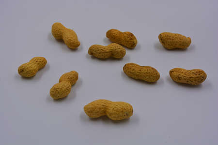 Natural peanuts in their own brown shell are located on a white background.