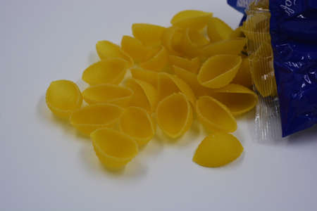 Italian yellow pasta made from durum wheat, vermicelli shells scattered over a white background.