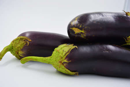 Fresh blue, purple eggplants recently picked and arranged on a matte white background. Delicious...