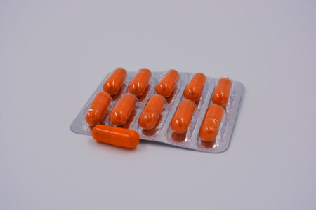 Medical preparations, medical pills in an orange capsule are located on a black background.
