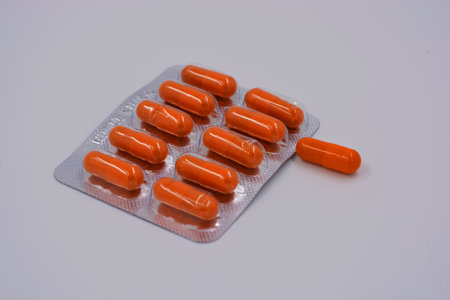 Medical preparations, medical pills in an orange capsule are located on a black background.